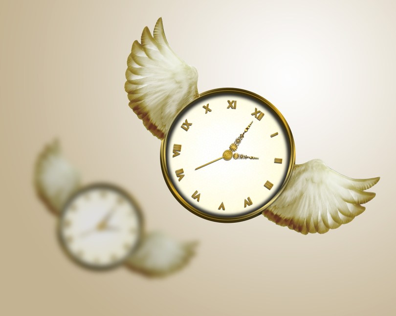A clock with wings flying in the air, with another one in the background out of focus. The background is a blurry tan.