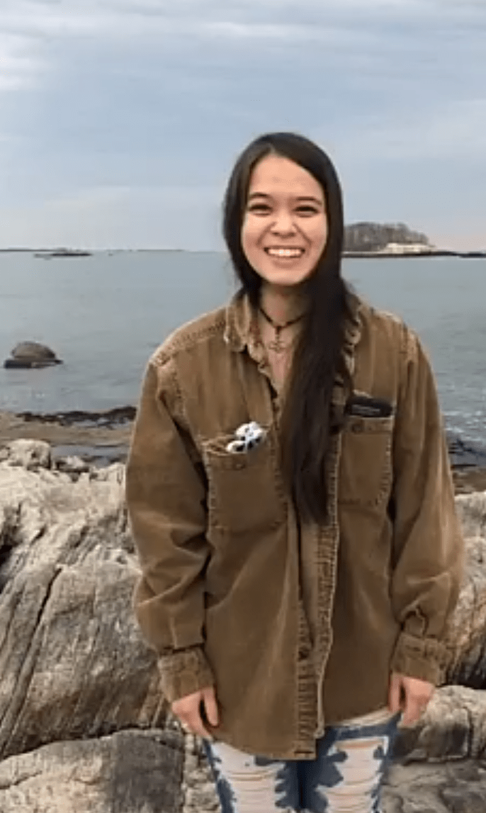 Woman standing on the ocean shoreline.