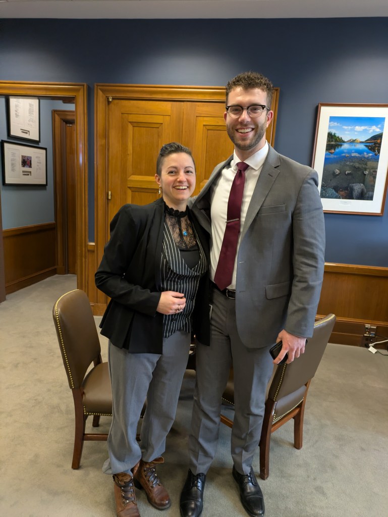 Two people in business suits posing for a photo in an office.